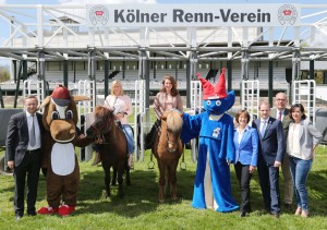 Startaufstellung zum Benefizrenntag 2016 mit den Verantwortlichen des Kinderschutzbundes Köln, des Kölner Renn-Vereins, GERMAN RACING, der Agentur macevent und Moderatorin Aleksandra Bechtel und Titelverteidigerin Mara Bergmann auf Islandpferden und Maskottchen Galoppi und Kibu.