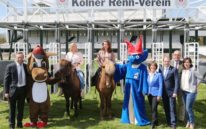 Startaufstellung zum Benefizrenntag 2016 mit den Verantwortlichen des Kinderschutzbundes Köln, des Kölner Renn-Vereins, GERMAN RACING, der Agentur macevent und Moderatorin Aleksandra Bechtel und Titelverteidigerin Mara Bergmann auf Islandpferden und Maskottchen Galoppi und Kibu.